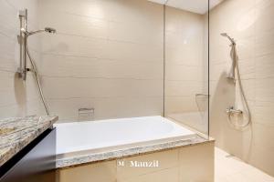 a bathroom with a shower and a white tub at Manzil - Lavish 3BR resort with private beach at Tiara Residence Palm Jumeirah in Dubai