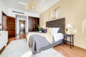 a bedroom with a large bed and a night stand at Manzil - Lavish 3BR resort with private beach at Tiara Residence Palm Jumeirah in Dubai