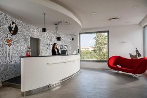 une femme assise à un comptoir de cuisine avec une chaise rouge dans l'établissement Mitico Hotel & Natural Spa, à Bologne