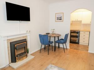ein Wohnzimmer mit einem Tisch, Stühlen und einem TV in der Unterkunft 50A Lloyd Street West in Llandudno