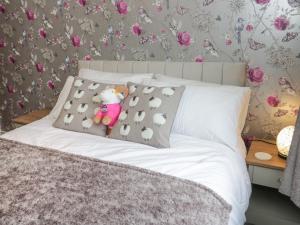 a bed with a teddy bear sitting on a pillow at 50A Lloyd Street West in Llandudno