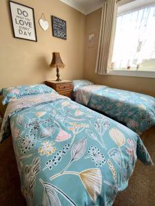 Minton cottage في Leadhills: غرفة نوم بسريرين مع لحاف ازرق