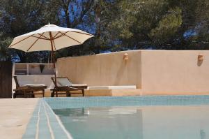 ein Pool mit einem Sonnenschirm, 2 Stühlen und einem Tisch mit einem Sonnenschirm in der Unterkunft La Madrugada Formentera by Tentol Hotels in Sant Ferran de Ses Roques