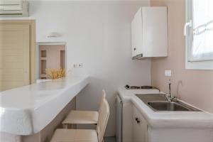 a white kitchen with a sink and a counter at Ninemia Suites Tinos Superior 101 in Kionia