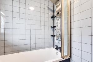 a white tiled bathroom with a tub and a mirror at Charming 2Bed Bungalow in Birkenhead in Birkenhead