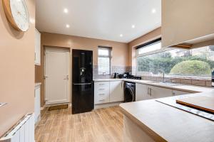 a kitchen with a black refrigerator and a window at Charming 2Bed Bungalow in Birkenhead in Birkenhead