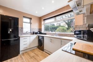 a kitchen with a black refrigerator and a sink at Charming 2Bed Bungalow in Birkenhead in Birkenhead