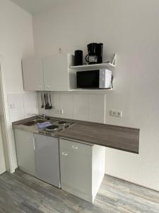 een kleine keuken met een aanrecht en een magnetron bij Apartments Osterstraße in Norden