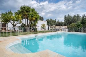 a swimming pool in a yard with a fence and trees at Casa Litali by Rentbeat in Ostuni