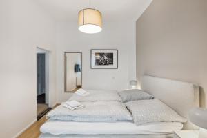 een witte slaapkamer met een bed en een spiegel bij Hotel 1A Apartment Berlin in Berlijn