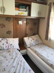 two twin beds in a small room with at Dymchurch Caravan Park on Romney Marsh in Dymchurch