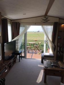 a living room with a television and a balcony at Dymchurch Caravan Park on Romney Marsh in Dymchurch