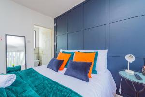 a bedroom with a large bed with orange and blue pillows at Luxury Studio Annexe, Heswall in Heswall