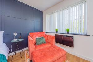 a bedroom with an orange chair and a tv at Luxury Studio Annexe, Heswall in Heswall