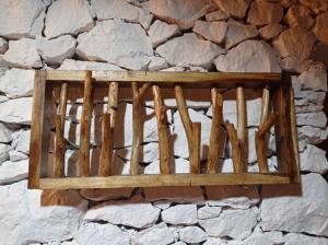 una estantería de madera colgada en una pared de piedra en Nirankara Nglolang Resort en Baron