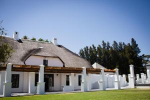 Cette maison ancienne est dotée d'un toit de chaume et d'une clôture blanche. dans l'établissement Manley Wine Estate, à Tulbagh