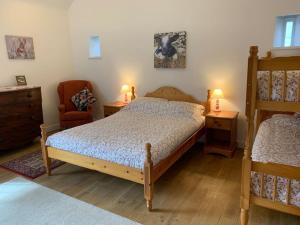 um quarto com uma cama, uma cadeira e 2 candeeiros em The Old Stables, Near Bakewell em Millers Dale