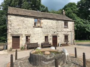a stone building with a fountain in front of it at The Old Stables, Near Bakewell in Millers Dale