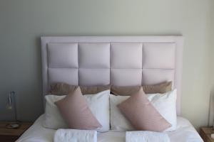 - un lit avec des oreillers et une tête de lit blancs dans l'établissement Home away from Home, à Windhoek