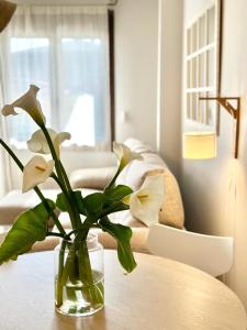 un vaso con fiori bianchi seduto su un tavolo di Apartamentos Noja Playa a Noja
