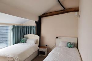 a bedroom with two beds and a window at 2 Bed Barn conversion in Tibenham