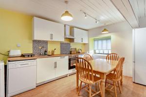 a kitchen with white cabinets and a table and chairs at 2 Bed Barn conversion in Tibenham