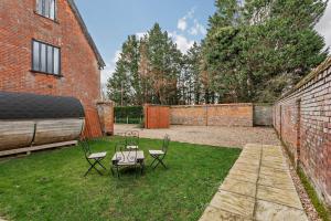 a patio with two chairs and a table in a yard at 2 Bed Barn conversion in Tibenham