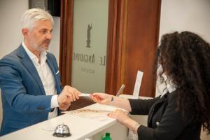 a man handing a woman a toothbrush in front of a mirror at Le Angioine Rooms in Naples