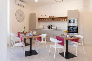 a kitchen with two tables and white chairs and a clock at Le Angioine Rooms in Naples