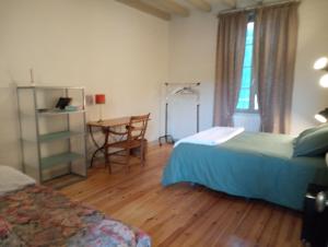 Castelmoron-sur-LotにあるLuluのベッドルーム1室(ベッド2台、テーブル、窓付)