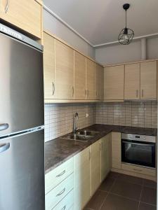 a kitchen with wooden cabinets and a sink and a refrigerator at EVa's Luxury Apartments No 3 in Áyios Spirídhon