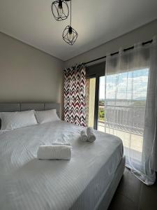 a bedroom with a white bed with a large window at EVa's Luxury Apartments No 3 in Áyios Spirídhon