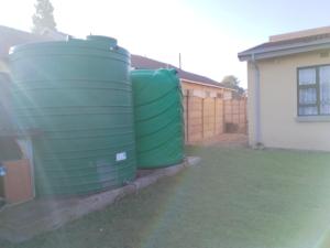 zwei grüne Wassertanks stehen neben einem Haus in der Unterkunft Tokelo Guesthouse Emalahleni in Witbank