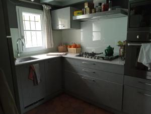 cocina con armarios blancos, fregadero y ventana en Lulu en Castelmoron-sur-Lot
