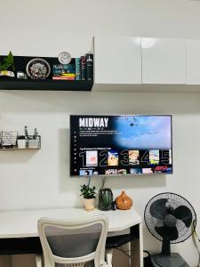 Elle comprend un bureau blanc avec 2 chaises et une télévision murale. dans l'établissement Lovely studio unit with fast Wi-Fi and Netflix, à Tagaytay