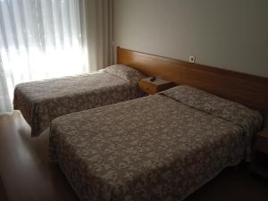 um quarto de hotel com duas camas e uma janela em Arcádia by Umbral em Fátima