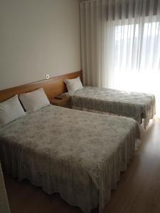 2 łóżka w pokoju hotelowym z oknem w obiekcie Arcádia by Umbral w Fatimie