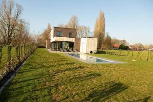 a house with a pool in the middle of a field at Villa Steedje in Jabbeke