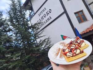 a person holding a plate of food with a dessert at Family Hotel Bansko Sofia in Sofia
