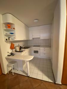 una pequeña cocina con armarios blancos y una mesa en Disentis-Ferien, en Disentis