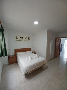 1 dormitorio con 1 cama con un cartel en la pared en Apartamentos Las Canteras Arena, en Las Palmas de Gran Canaria
