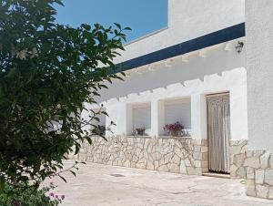 un edificio blanco con 2 ventanas y una pared de piedra en Casa Rural Los Marqueses, en Valmuel