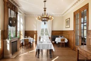 una sala da pranzo con tavoli e lampadario pendente di Château Charles a Pepinster