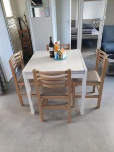 a white table with two chairs and a bottle of wine at MobilHome Les Dunes de Contis in Saint-Julien-en-Born