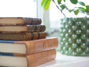 una pila de libros sentados en una mesa con un jarrón en Stora Hotellet Markaryd, en Markaryd