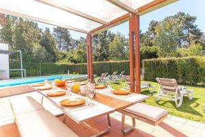 a patio with a table and chairs and a pool at Villa Aroeira II in Aroeira