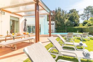 a patio with chairs and a table and a pool at Villa Aroeira II in Aroeira