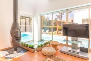 a living room with a tv and a swimming pool at Villa Aroeira II in Aroeira