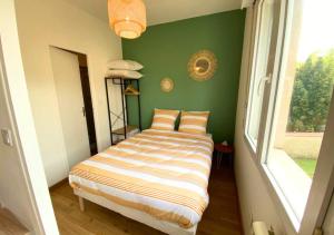 uma cama num quarto com uma parede verde em Au 45' - Poitiers - Futuroscope - La Conciergerie em Poitiers