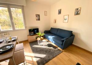 ein Wohnzimmer mit einem blauen Sofa und einem Tisch in der Unterkunft Au 45' - Poitiers - Futuroscope - La Conciergerie in Poitiers